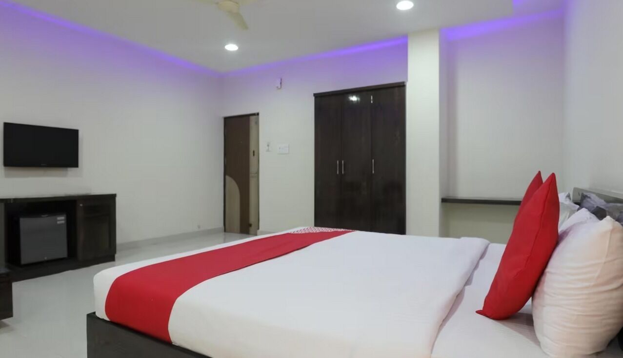 Quarto com cama, televisão, guarda-roupa e ventoinha no teto.