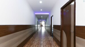 A long, narrow hallway with wooden flooring and walls, leading to a door marked with the number 306.
