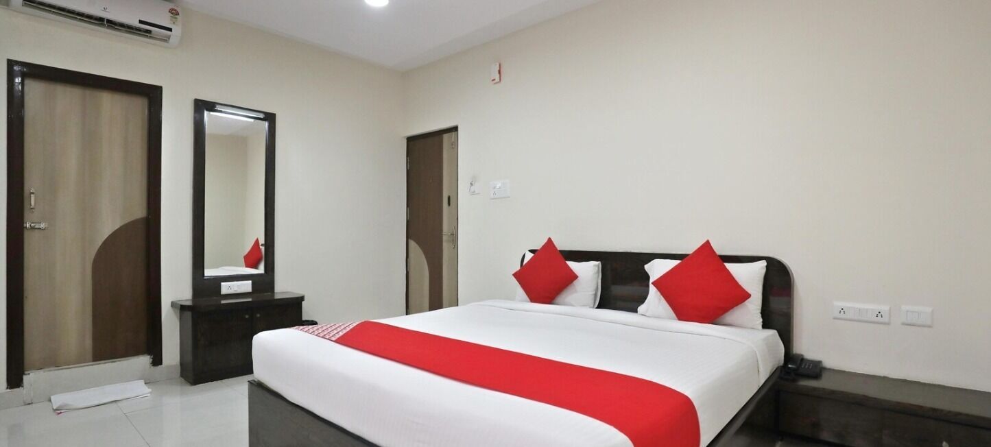 Ein Hotelzimmer mit einem großen Bett, einem Nachttisch, einem Spiegel und zwei Türen.
