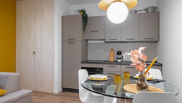 A modern kitchen with grey cabinets, a black countertop, and a hanging light fixture. - Cascina Conicchio 1 (Brescia)