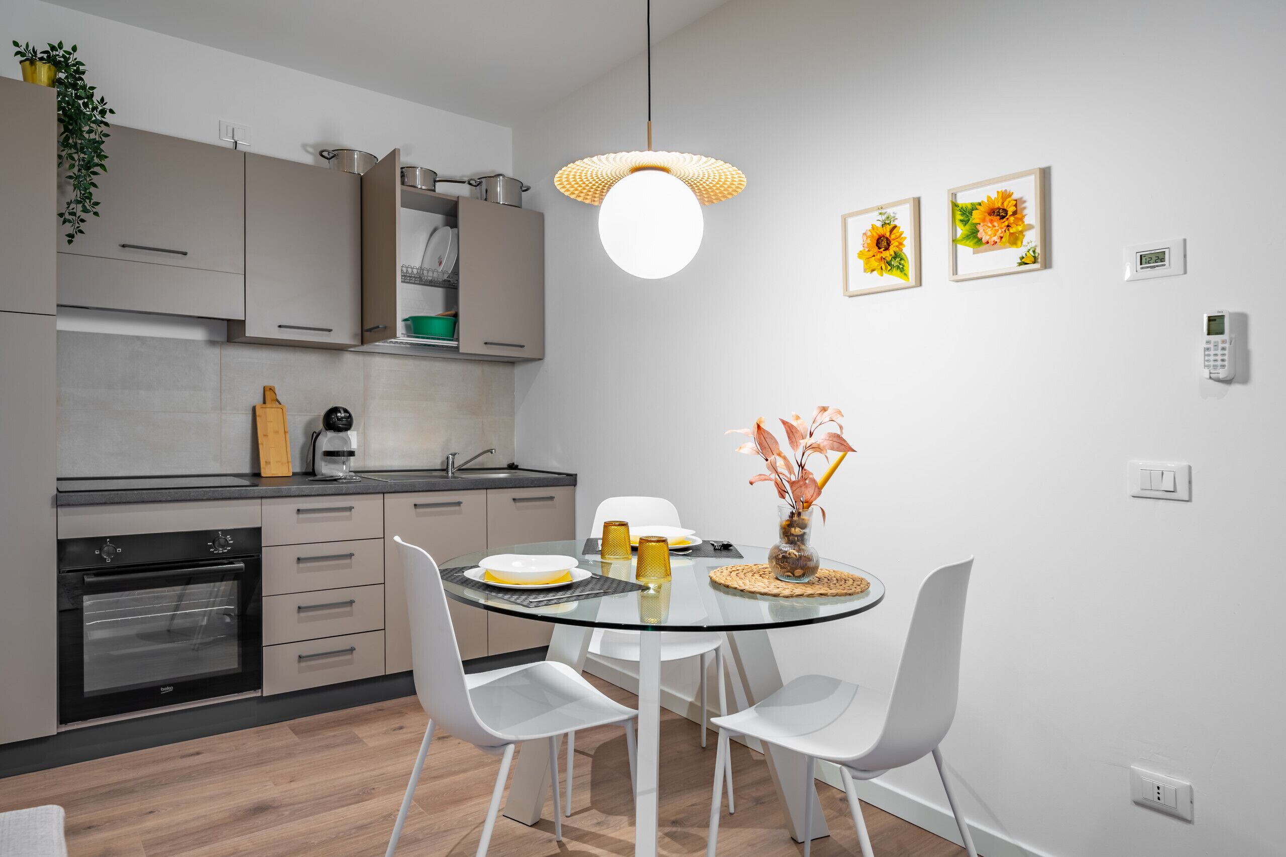 Una cucina moderna con un tavolo da pranzo in vetro, sedie bianche e un lampadario.