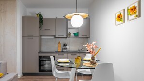 A modern kitchen with white cabinets, a glass dining table, and white chairs. - Cascina Conicchio 1 (Brescia)