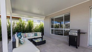 A covered patio with a sofa, coffee table, and a grill station. - Luxury on Lesmurdie - Close to Zoo & Golf Club (Dubbo)