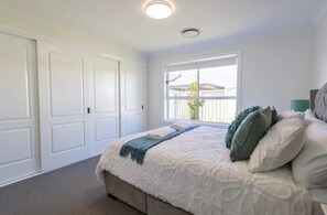 Ein Schlafzimmer mit einem großen Bett, einem Fenster mit Aussicht und weißen Wänden.