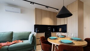 A modern kitchen with wooden cabinets, a black countertop, and a dining area with a round table and chairs. - Cuero Centrum Gara Podziemny Dwie Sypialnie (Bydgoszcz)
