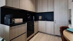 A modern kitchen with wooden cabinets, a black countertop, and a built-in oven. - Cuero Centrum Gara Podziemny Dwie Sypialnie (Bydgoszcz)