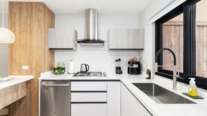 A modern kitchen with white cabinetry, stainless steel appliances, and a black faucet. - Minutes to the Beach | Porta Al Sole 10 by Bocobay (Noord)