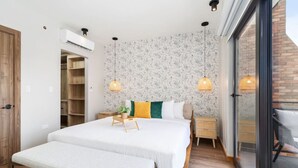 A modern bedroom with a large bed, bedside tables, a bench, and a sliding glass door to a balcony. - Minutes to the Beach | Porta Al Sole 10 by Bocobay (Noord)