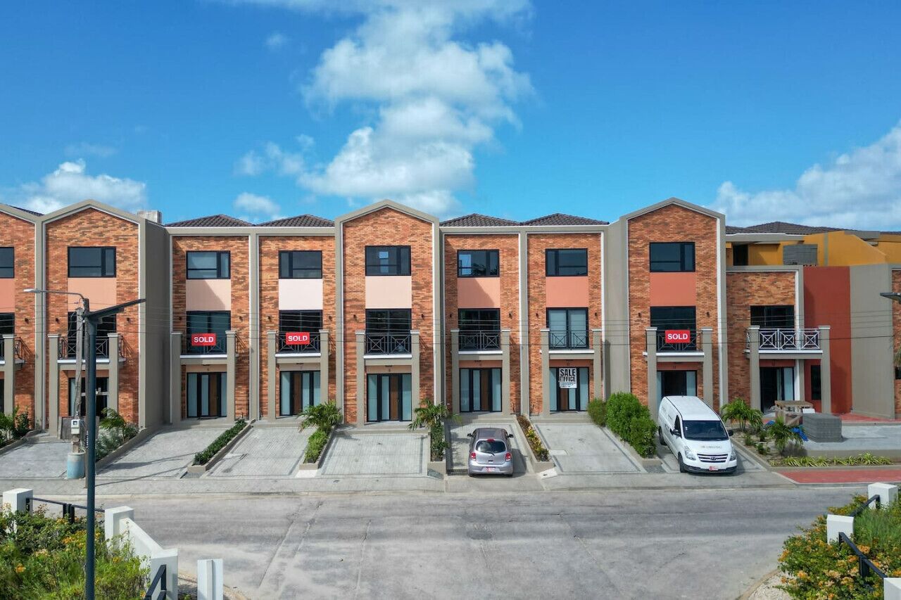 A row of townhouses with 'SOLD' signs, a parking area, and a white van parked in front.