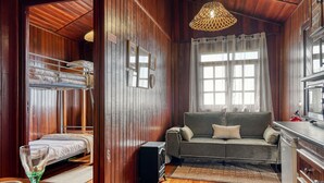 A cozy room with a bunk bed, a sofa, a dining table, and a kitchen area. - Chalet do Relógio d’Água, a Home in Madeira (Ponta do Sol)