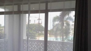 Une chambre avec un lit, une vue sur une piscine et un balcon agrémenté d’une balustrade.