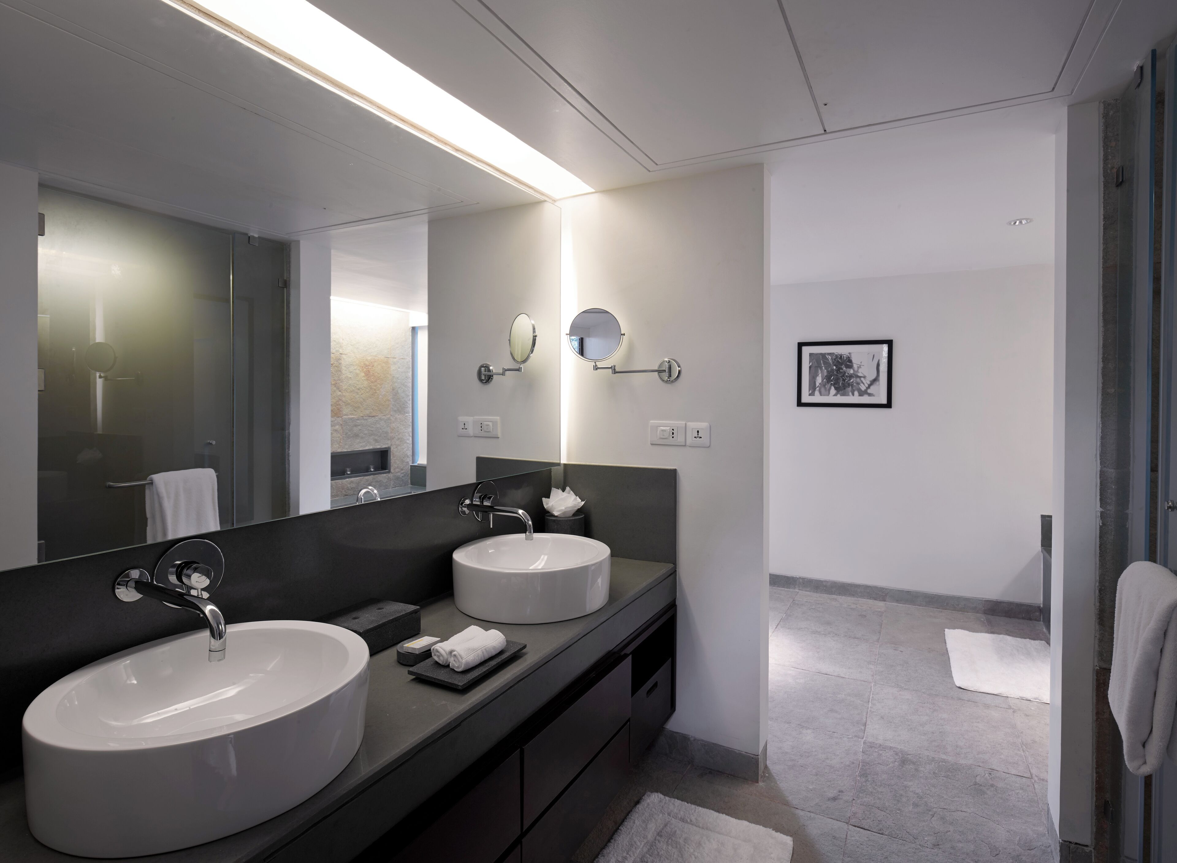 Un baño moderno con dos lavamanos, un espejo grande y una zona de ducha.