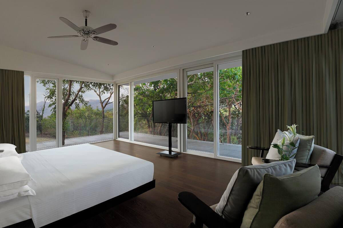 A modern hotel room with a large bed, a flat-screen TV, and a ceiling fan.
