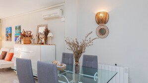 A modern living room with a glass dining table, grey chairs, a white sofa, and decorative wall art. - Edificio Luxor II by Interhome (Miami Platja)