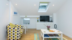 Ein modernes Wohnzimmer mit Sofa, Couchtisch, Fernseher und Küchenzeile.