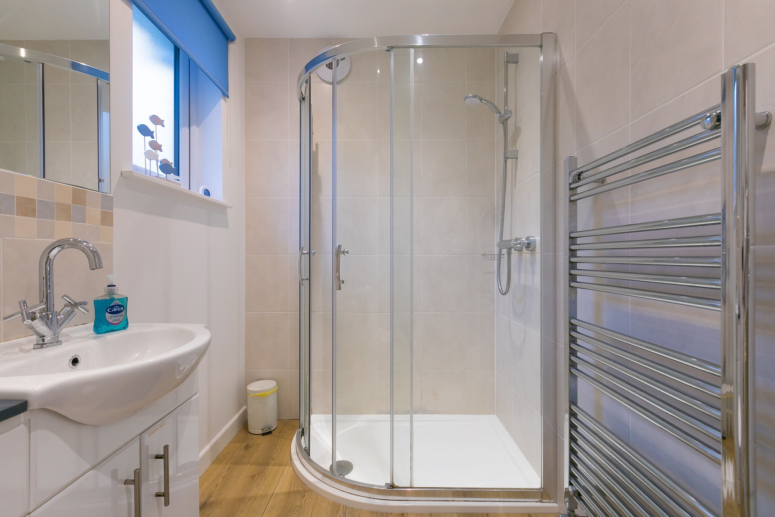 Un baño moderno con ducha de vidrio, lavamanos blanco y toallero.