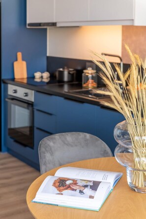Une cuisine moderne avec des meubles de couleur bleu foncé, un plan de travail en bois et un vase contenant des tiges de blé.
