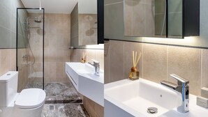 A modern bathroom with a glass-enclosed shower, a white toilet, and a vanity with a large sink and mirror.