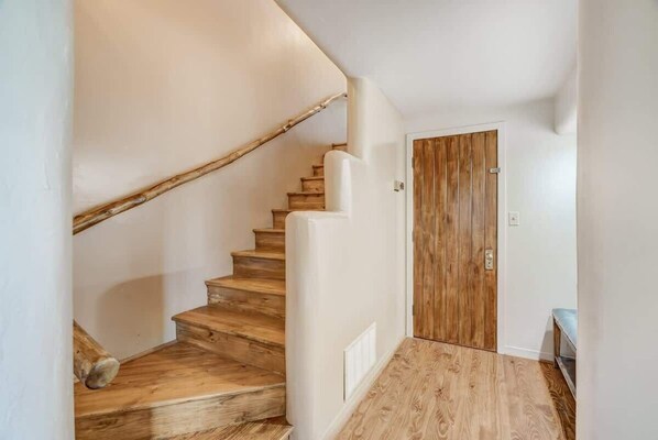 Un escalier en bois mène à une porte dotée d’un cadre blanc.