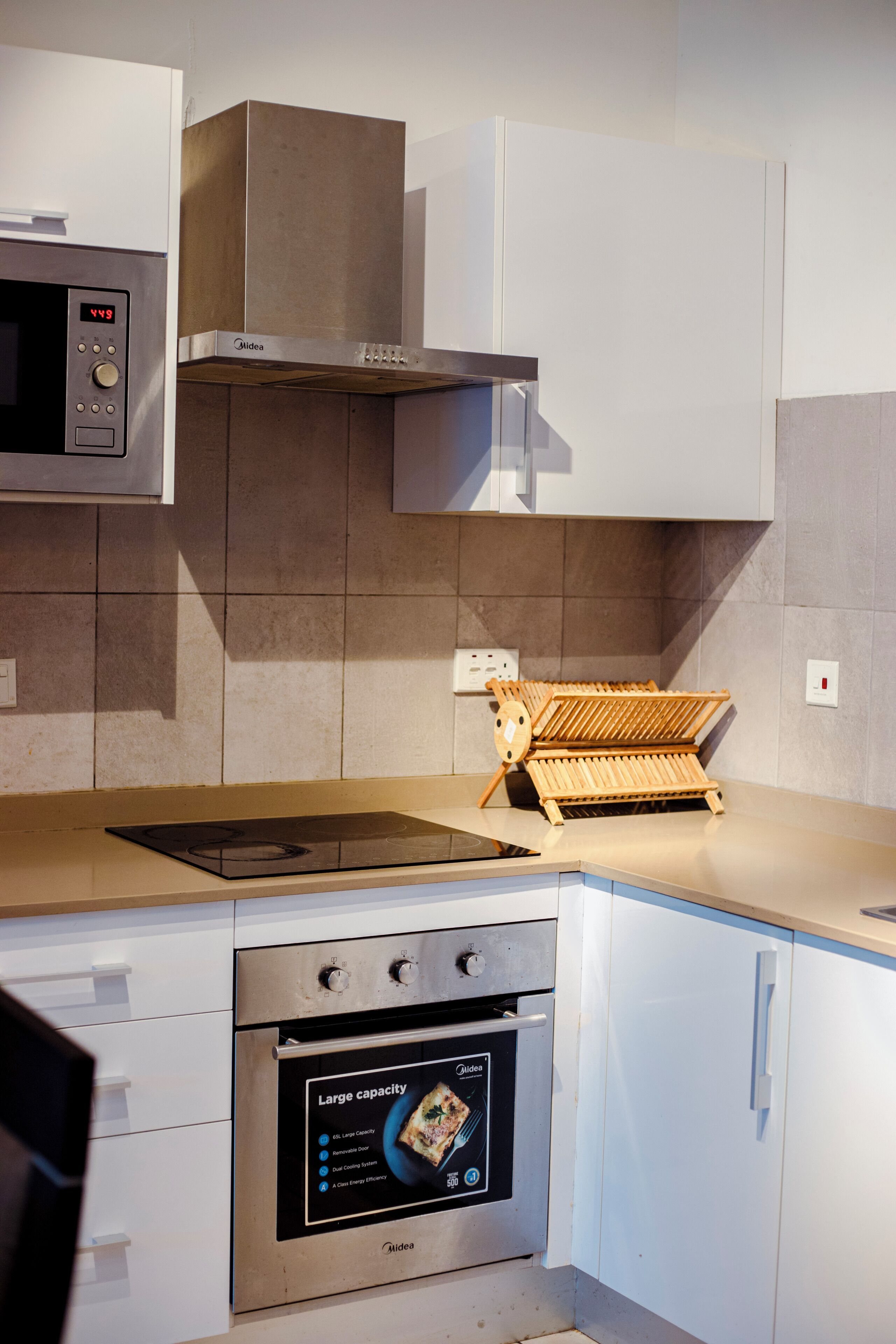 A kitchen with a built-in microwave, oven, and a wooden rack.