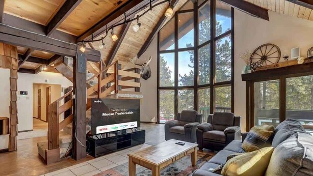 A cozy cabin interior with a large TV screen, wooden beams, and a rustic decor. - Moose Tracks Cabin! Secluded Mtn Retreat w/HotTub (Woodland Park)
