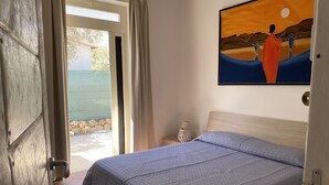 Un dormitorio con cama, un cuadro, una mesita de noche y vistas al exterior.