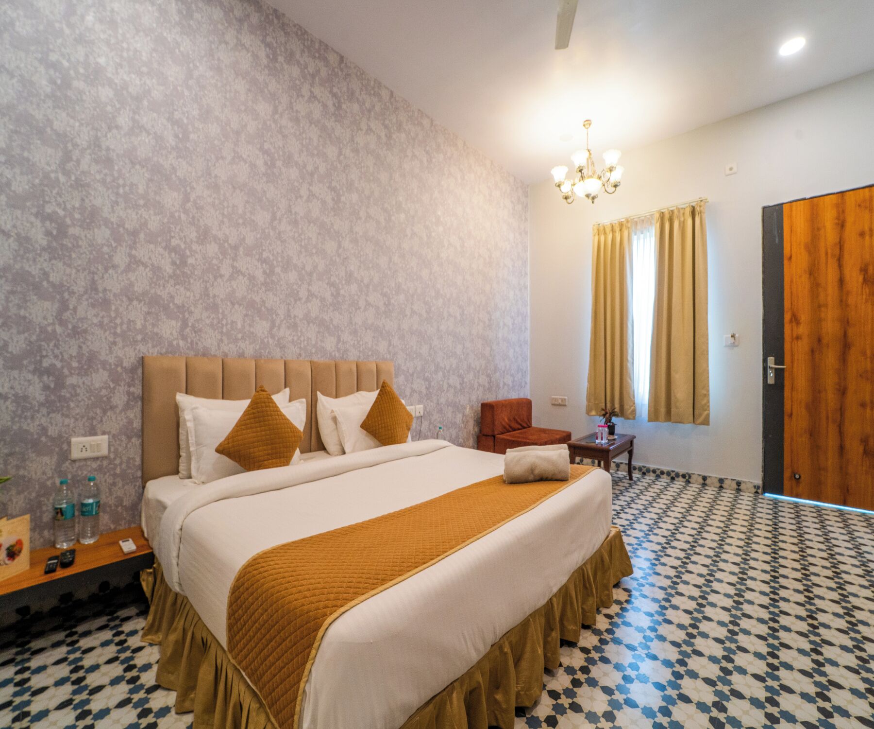 Una habitación de hotel con una cama grande, una puerta de madera y un suelo con estampado.