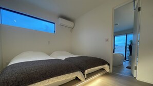 A bedroom with a bed, a window, an air conditioning unit, and a view of the outside. - BBQ (Mihama)