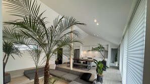 A modern living room with a sofa, a dining table, and a kitchen in the background. - BBQ (Mihama)