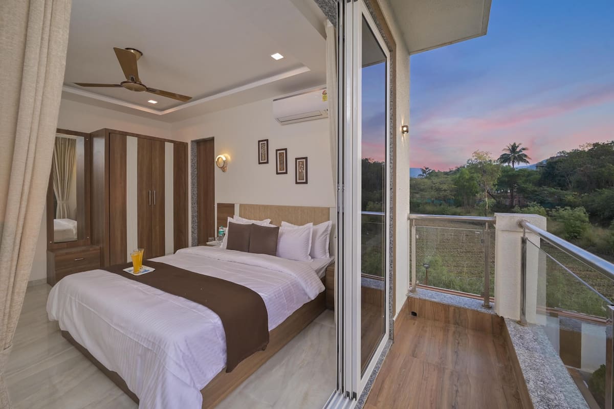 A bedroom with a bed, bedside table, and a view of the outdoors.