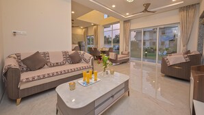 A modern living room with a sofa, coffee table, and dining area. - Vivanta Villa (Mawal)