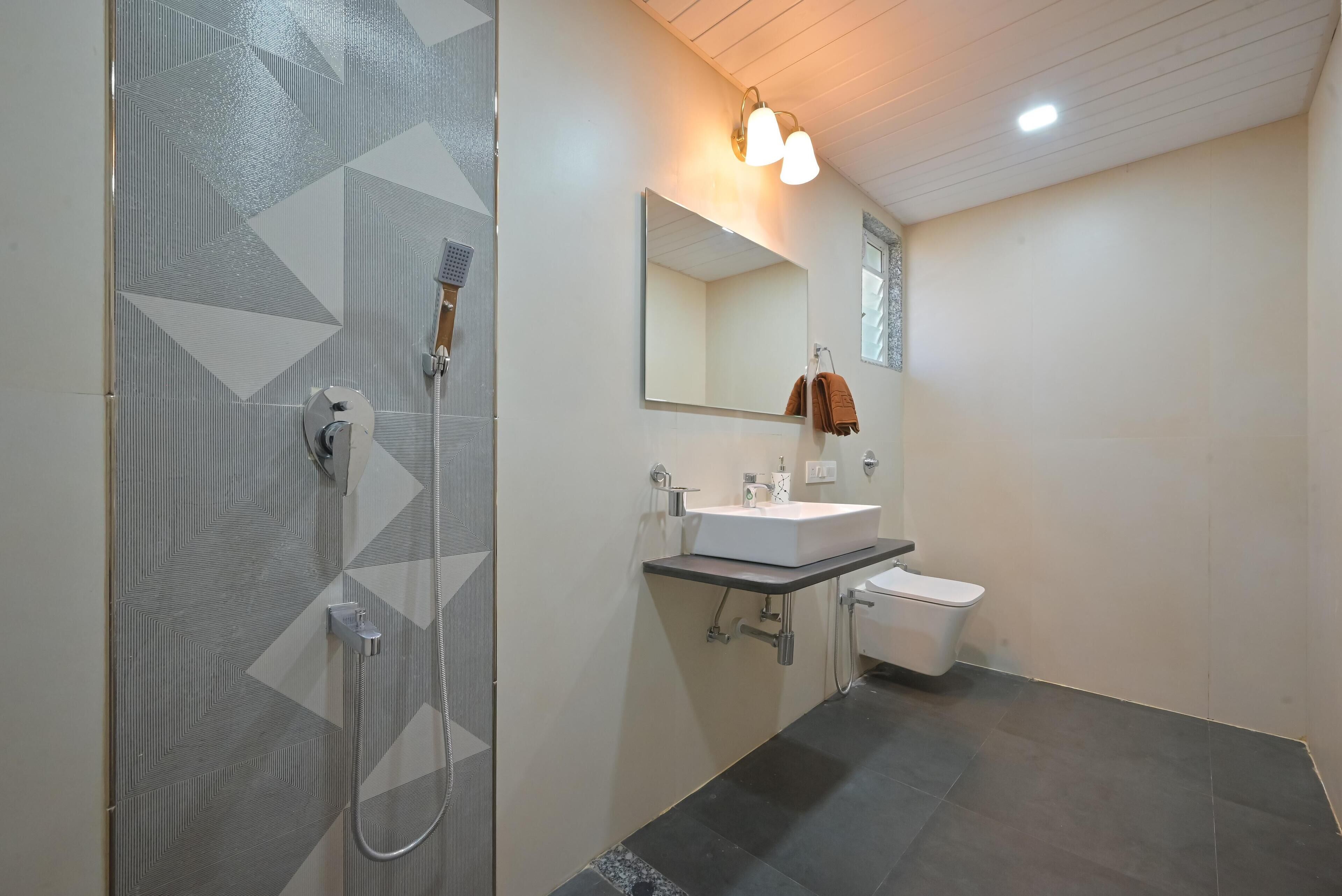 A modern bathroom with a shower, sink, and toilet.