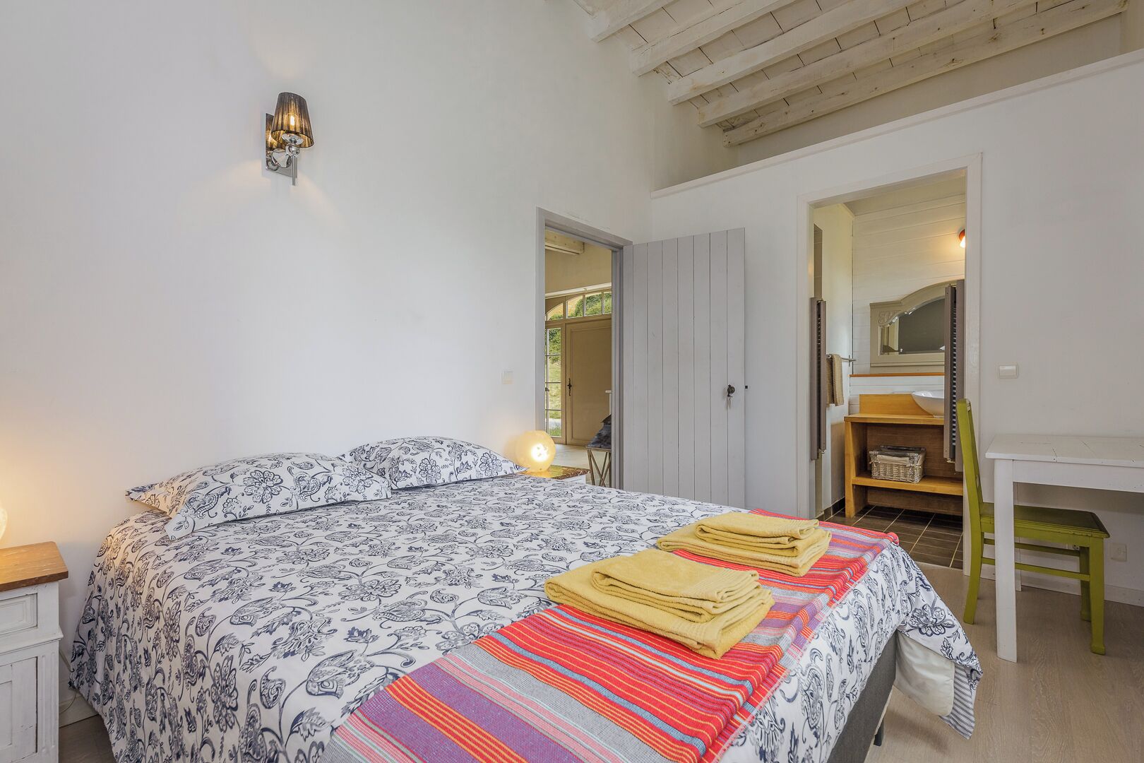 Une chambre à coucher comprenant un lit, une table de chevet, une chaise, un bureau et un miroir.