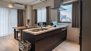 Een moderne keuken met een centraal eiland, een RVS-spoelbak en een stadszicht door grote ramen.