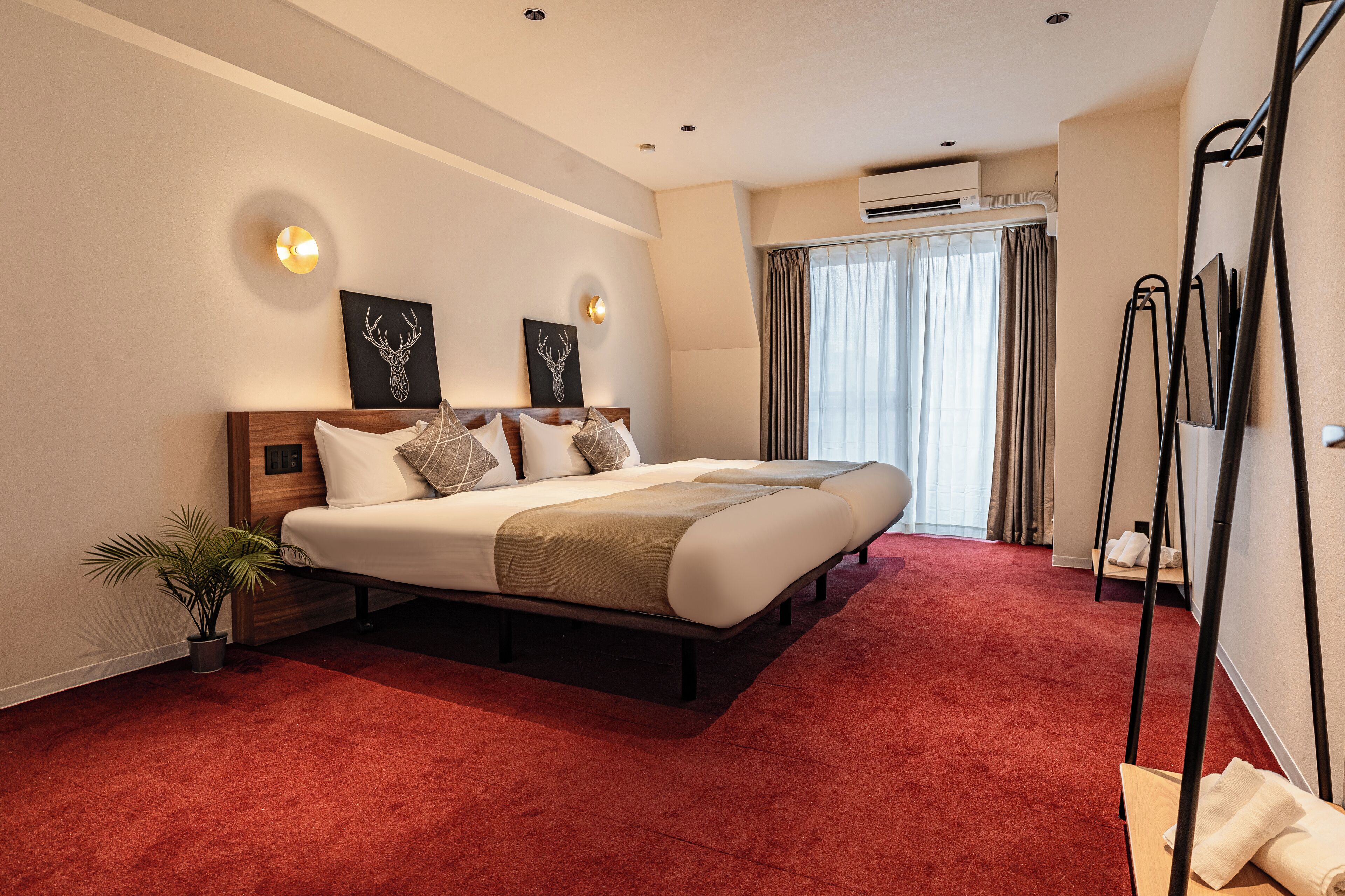 A spacious bedroom with a large bed, a potted plant, and a standing heater.