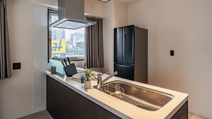 Een moderne keuken met een inbouwspoelbak, een roestvrijstalen koelkast en een raam met gordijnen.