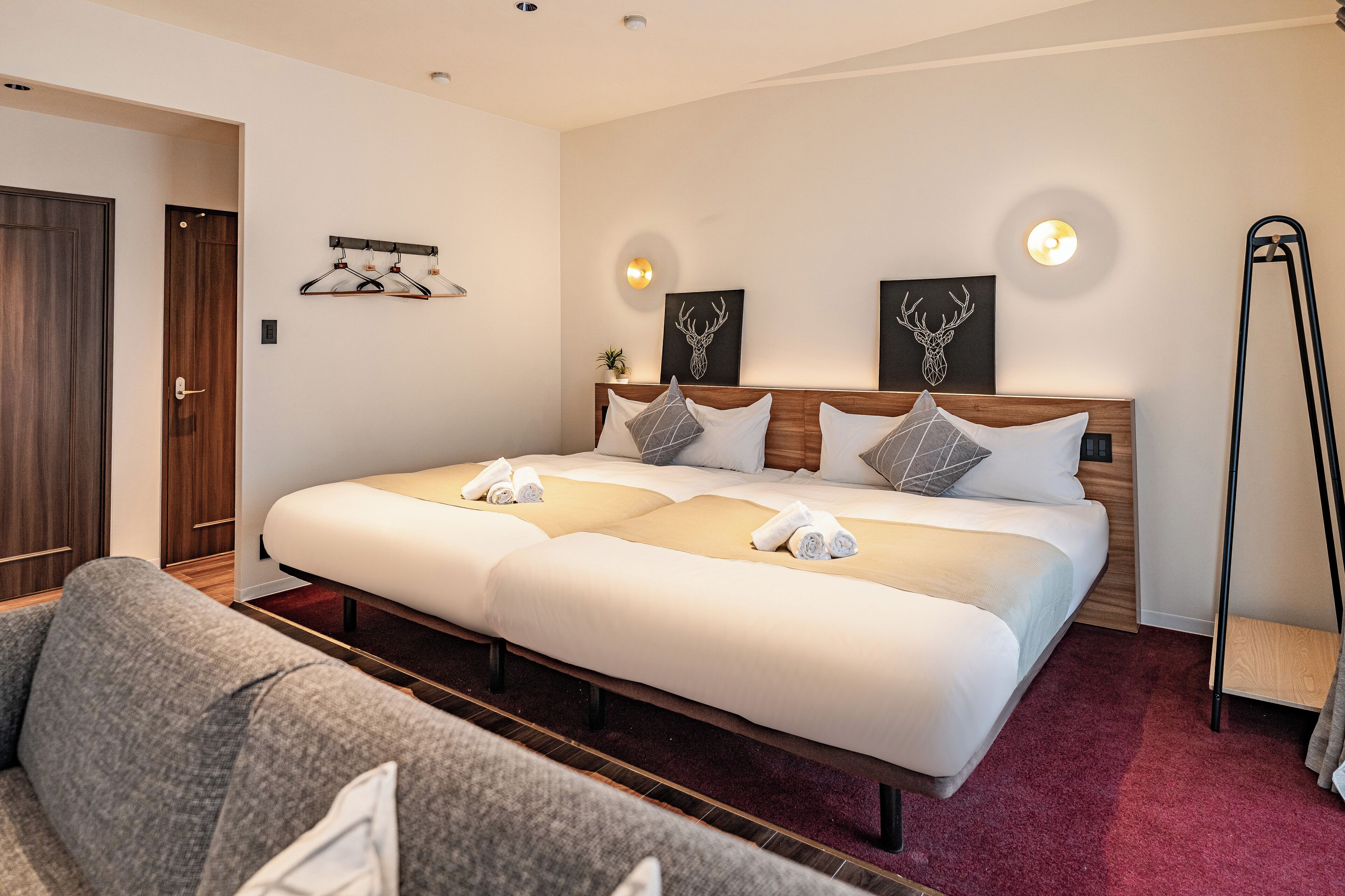 Una habitación de hotel con una cama grande, un sofá gris y un armario de madera.