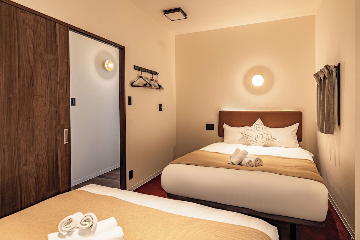Une chambre d’hôtel avec un grand lit, une armoire en bois, un porte-serviettes fixé au mur et un luminaire au plafond.
