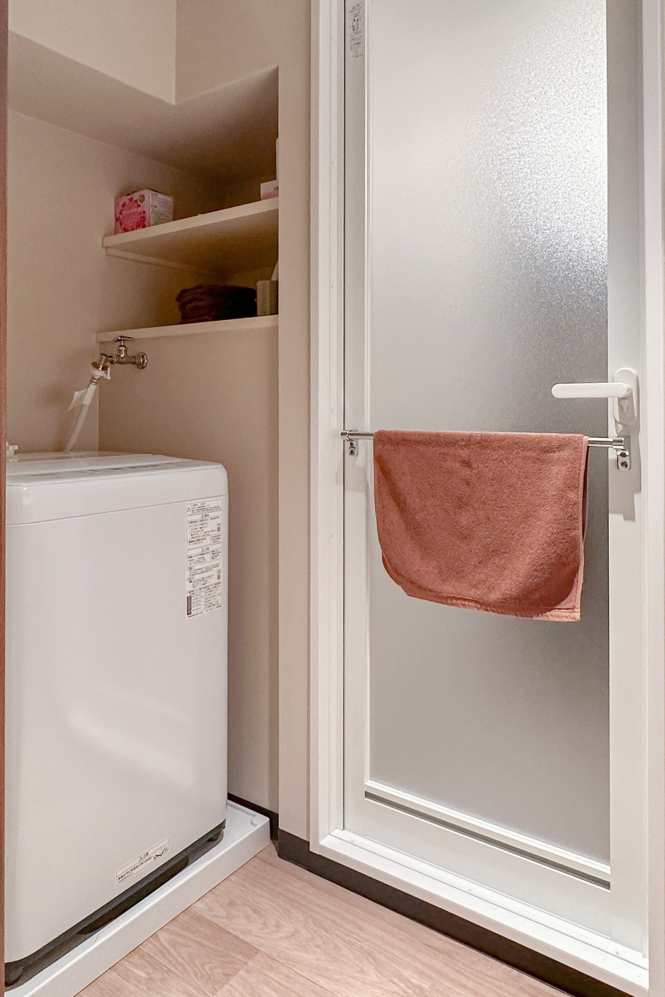 Ein Badezimmer mit einer weißen Waschmaschine, einem Handtuchhalter mit Handtuch und einem Ablagebereich für Toilettenartikel.