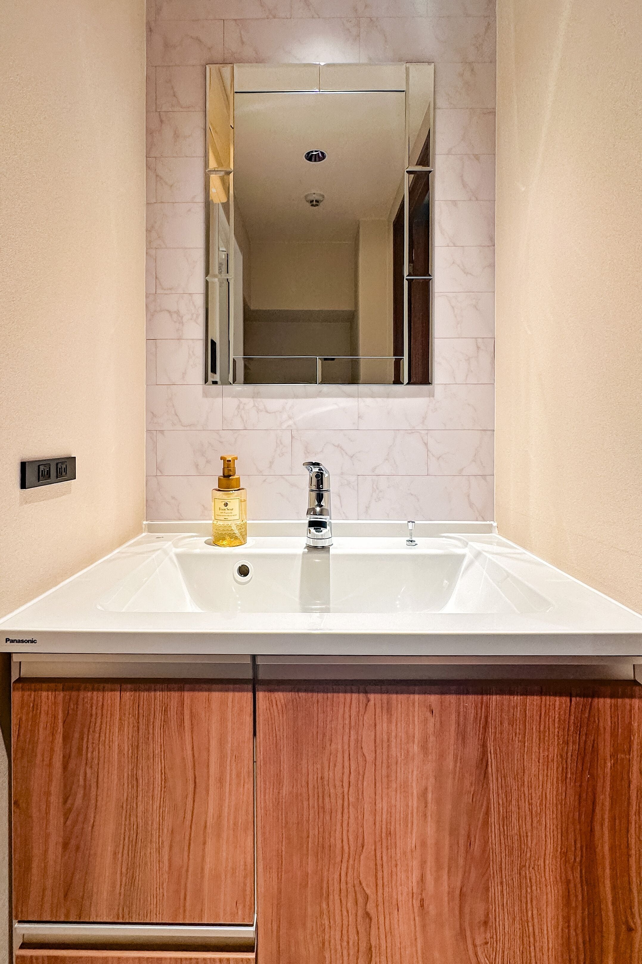 A bathroom with a white sink, a mirror above it, and a wooden cabinet below.