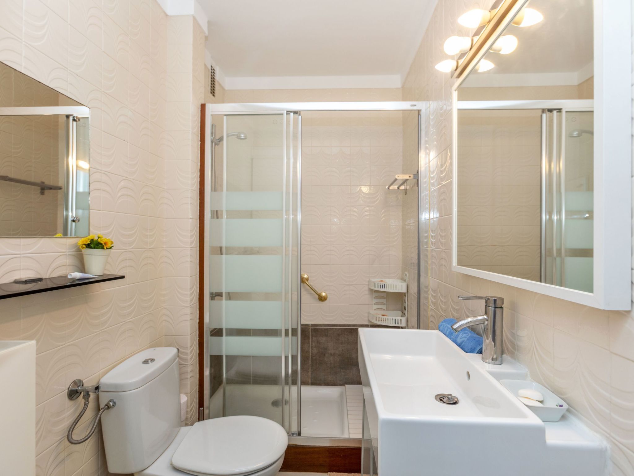 A bathroom with a toilet, sink, shower, and a mirror.