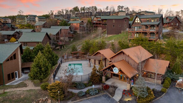 A resort with multiple wooden buildings, a central pool, and a well-maintained landscape. - Bear Cove by AvantStay | Hot Tub + Pool Table | In the Heart of Pigeon Forge (Pigeon Forge)
