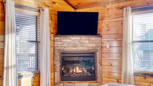 A cozy room with a fireplace, wooden walls, and a flat-screen TV mounted above it. - Bear Cove by AvantStay | Hot Tub + Pool Table | In the Heart of Pigeon Forge (Pigeon Forge)