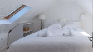 A modern, white-themed bedroom with a skylight, a neatly made bed, and a bedside table. - Ker Hir - Charming comfortable Breton house (Landunvez)