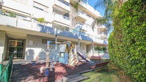 A playground with slides and climbing structures, a bench, and a green hedge. - Impressive penthouse in the port of Denia. (Denia)
