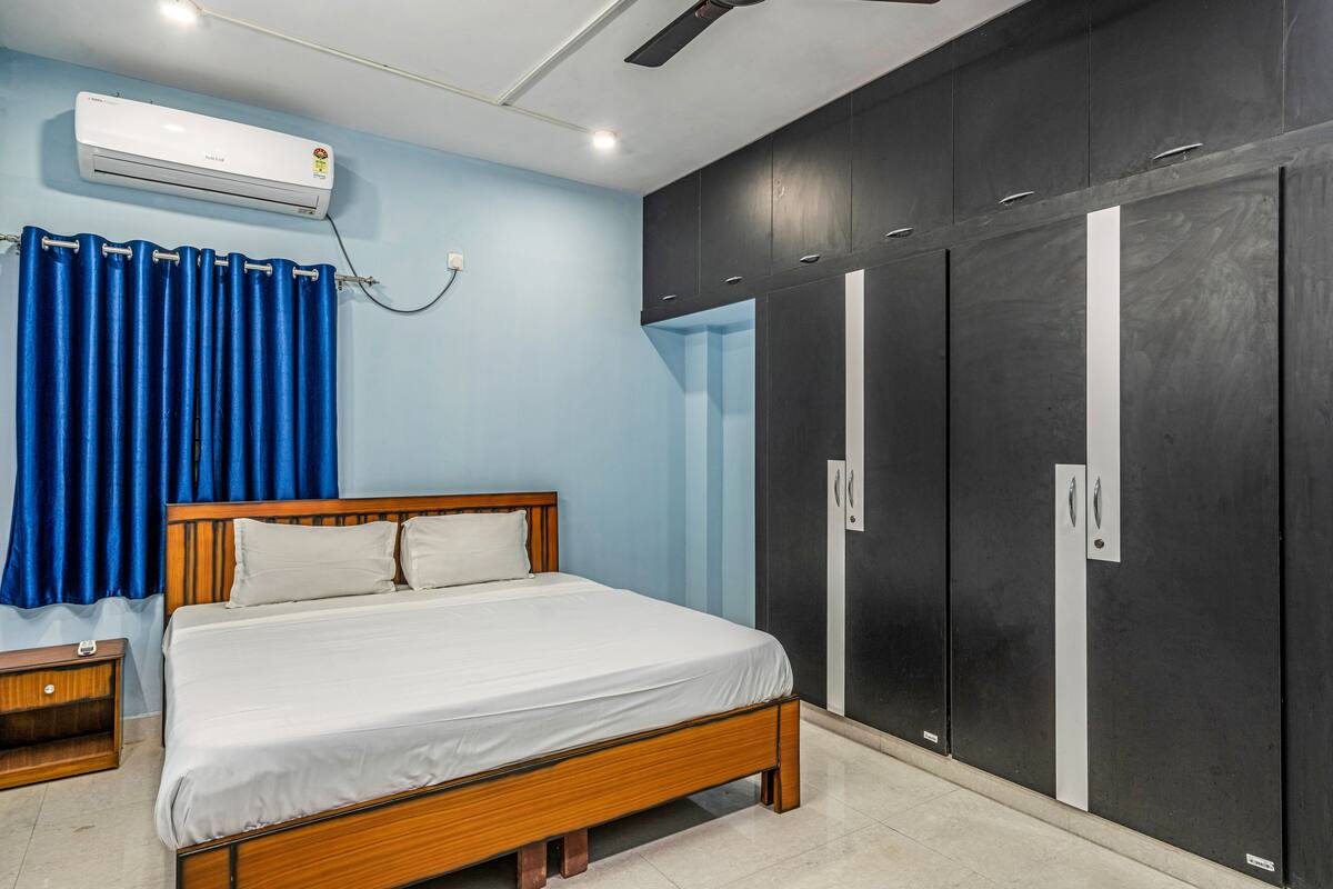 A bedroom with a bed, a wardrobe, and an air conditioning unit.