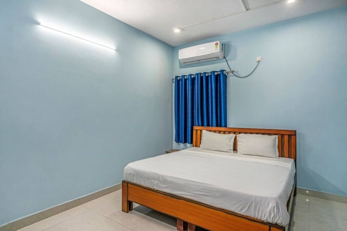 A bedroom with a wooden bed, a blue curtain, and an air conditioning unit on the wall.