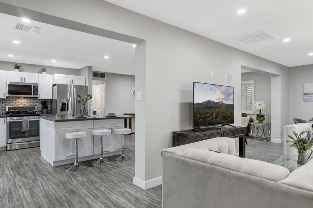 A modern kitchen with white cabinets, stainless steel appliances, and a central island with bar stools.