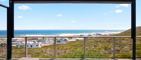 A balcony with a view of the ocean and coastal buildings.