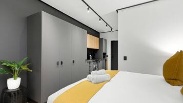 Una habitación de hotel moderna con una cama grande, un baño pequeño y una kitchenette.